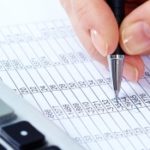 Image of female hand with pen over financial document